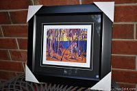 Framed and matted colorful forest scene art print titled "Phantom Tent" by Tom Thomson shown with protective corner covers on frame.
