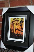 Full view of the framed "Pine Trees and Sunset" print in a black frame with black and white mats.