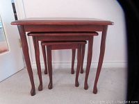 Set of three vintage wooden nesting tables, stacked inside each other, showing cabriole legs and scalloped edges
