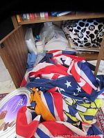 Cupboard interior showing several colorful folded flags in red, white, blue, yellow, and more.