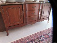 Front view of the full mahogany buffet showing three drawers center and two carved door cabinets on each side, with metal handles and decorative legs.
