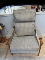 Front view of the mid-century modern teakwood upholstered chair showing full seat, back cushions, and armrests with striped fabric upholstery.