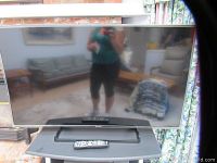 Front view of Panasonic 50 inch LED LCD TV with remote on stand, showing screen and reflection.
