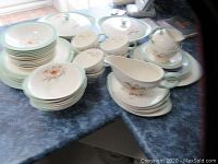 Partial set of various Wedgwood Tiger Lily dinnerware pieces arranged on table showing plates, cups, bowls, covered dish, and gravy boat