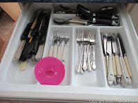 Drawer with knives, forks, spoons, and cream-handled knives arranged in plastic organizer