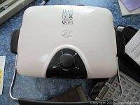 Off-white George Foreman electric grill closed, showing top surface and control dial.