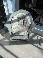 Front view of the gray wicker rocking armchair showing floral cushion and woven wicker.