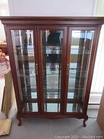 Front view of the wooden display cabinet showing three glass doors with wood frame and mirrored back panel