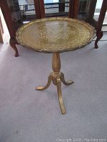 Full view of the round pedestal table showing scalloped edge and gold finish.