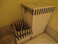 Two woven wooden baskets, tall one with hinged lid and smaller square one, both with blue and white striped fabric liners.