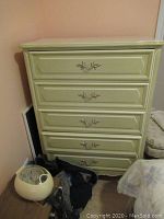 Front view of French Provincial style chest of drawers showing paint color, five drawers, and decorative metal handles.