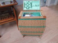 Closed wicker sewing basket with green woven stripe decoration and tufted satin lid interior