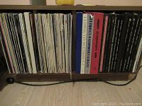 Photo of vinyl records arranged vertically in a wooden cabinet showing variety in sleeve colors and some visible titles of composers