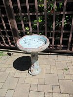 Front and top view of the resin bird bath showing the scalloped basin and textured tree trunk pedestal.