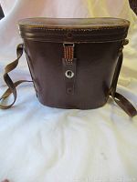 Brown leather binocular carrying case, closed, showing wear.