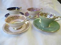 Four teacups with saucers arranged on white background showing exterior colors and patterns