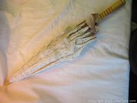 Closed lace parasol showing the wooden handle and delicate lace fabric folded along the ribs.