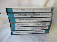 Stack of six boxed Coalport commemorative plates with visible label details for each plate's historical scene and edition info.