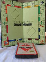 Photo showing open vintage Monopoly board with classic British property names and starter positions visible, with the box positioned in front.