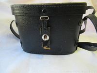 Black leather binocular carrying case with strap, showing exterior wear, snap closure and leather tab.
