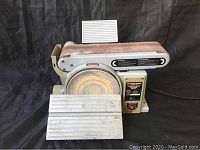 Front view of the belt and disc sander showing the 8 inch sanding disc, work table, and sanding belt.
