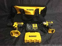 Shows full lot with two tools, charger, batteries, and carrying bag on black cloth backdrop.