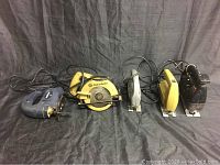 Overview of all five saws arranged on a black fabric background. Visible jigsaws and circular saw, cords untangled.