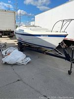 Port bow view of white fiberglass sailboat on black steel trailer with winch and jack stand