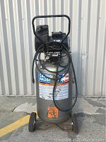 Full front view of vertical air compressor on wheels and handle