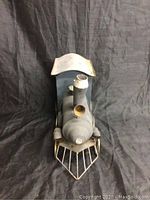 Front view of the toy train showing the smokestack, cowcatcher, and cab with paint peeling.