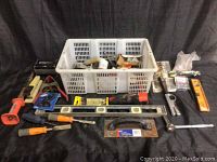 Wide shot of the lot showing white plastic basket containing various tools and hardware, and multiple hand tools laid out in front including screwdrivers, hammer, pliers, levels, and tape measure.