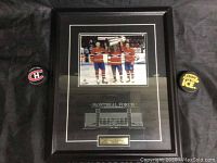 Framed Montreal Forum print with superimposed photo of Canadiens players and two hockey pucks positioned on either side.