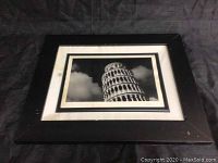Framed photo of the Leaning Tower of Pisa in a black frame with some stains and water damage visible on the white matte and frame edges
