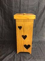 Front view of wooden garbage bin with three heart-shaped cutouts.,