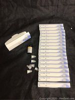 Wide shot of lot displaying 17 boxes of NoVo Fine Plus 32G 4 mm injection needles, one bottle of One Touch Verio test strips, and several loose needles with caps.