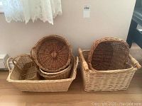 Group of assorted wicker baskets including rectangular and round shapes stacked inside larger rectangular basket.
