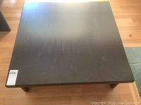 Top view of the square dark wood coffee table showing flat smooth surface with minor marks.