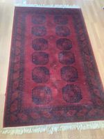 Full view of red wool area rug laid flat on floor