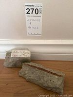 Two concrete pieces claimed to be Berlin Wall fragments, placed on wooden surface, one labeled.