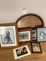 Photo of round wooden framed mirror with some Hawaiian-themed framed prints and photos in the background