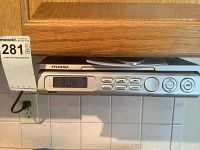 Front view of the Sylvania under counter CD radio with digital clock display, buttons, and power cord.