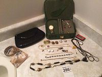 Overview of all jewelry items including necklaces, bracelets, pins, a pouch, and men's watch box with watch and cufflinks.