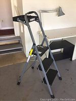 Full view of the three-step ladder showing metal frame and black treads.