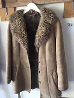 Front view of the full suede coat with shearling collar and button closure