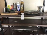 Warming tray on lower shelf with pewter items on upper shelf including plate, candle holder, and tankards