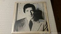 Front cover of Leonard Cohen vinyl album 'New Skin for the Old Ceremony' showing black and white portrait of Leonard Cohen in suit.