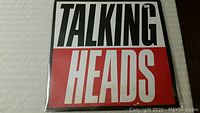 Front cover of the Talking Heads vinyl album "True Stories" displayed flat on a white quilted surface.