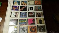 40 music CDs arranged in rows on white surface, showing front covers with artwork and artist photos. Mostly 90s and 2000s albums with varied genres.