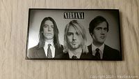 Front cover of Nirvana box set with black and white image of the three band members in suits.