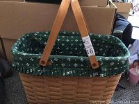 Full view of Longaberger woven basket featuring green fabric liner and wooden handles in upright position.
